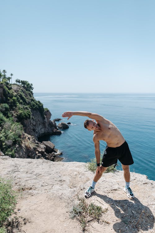 Topless Man Doing Stretching on a Cliff