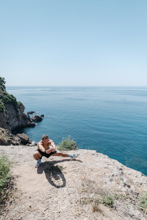 Shirtless Person Doing Stretching on a Cliff