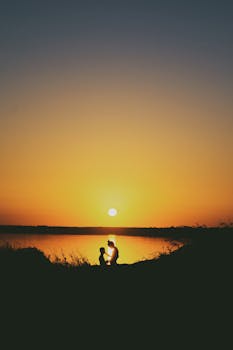 A couple shares a romantic moment by the lake during a stunning sunset in Ukraine.