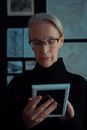 Man in Black Crew Neck Shirt Wearing Black Framed Eyeglasses Holding White Tablet Computer