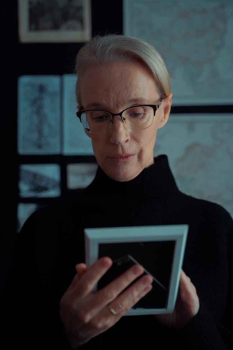 A Woman Looking At A Picture Frame 