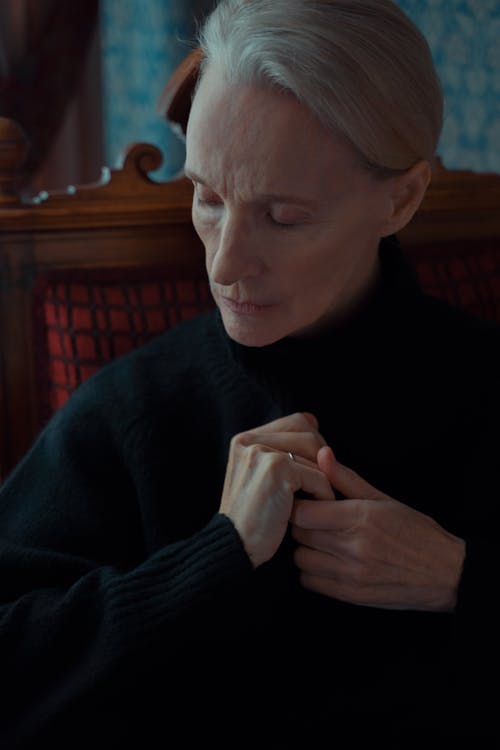 Elderly Woman in Black Dress Sitting on Wooden Chair Feeling Sad