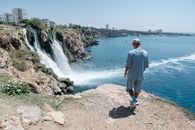 Man in White Robe Standing on Rocky Shore