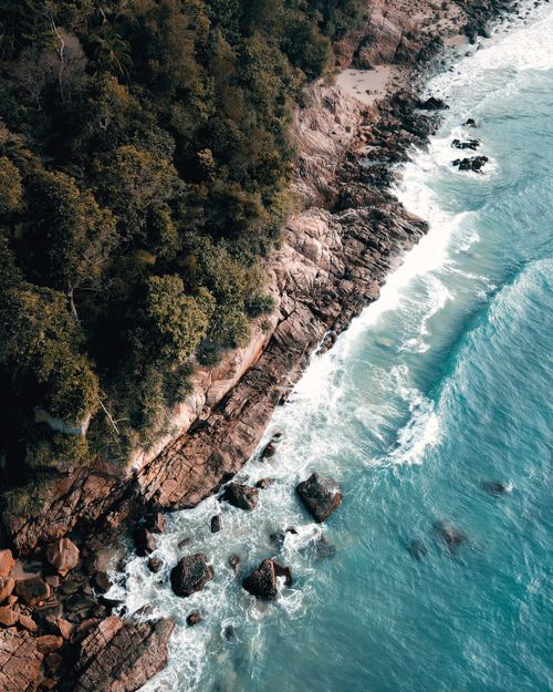 Free Dramatic aerial shot of the rocky coastline in Chukai, Terengganu, Malaysia with vibrant blue waves. Stock Photo