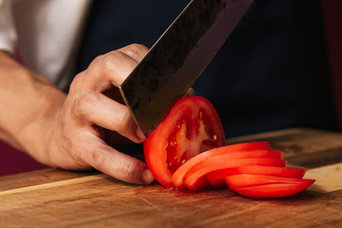 Free A Person using Knife while Slicing Tomatoes Stock Photo