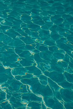 Captivating pattern of sunlit teal water ripple highlights, evoking tranquility and serenity.