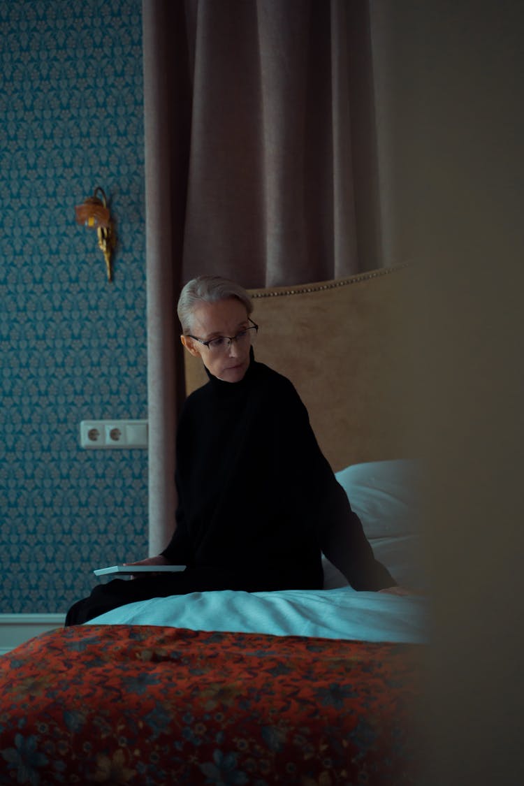 An Elderly Woman Sitting On The Bed