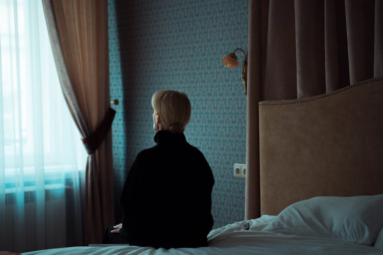 A Woman Sitting Alone On Her Bed