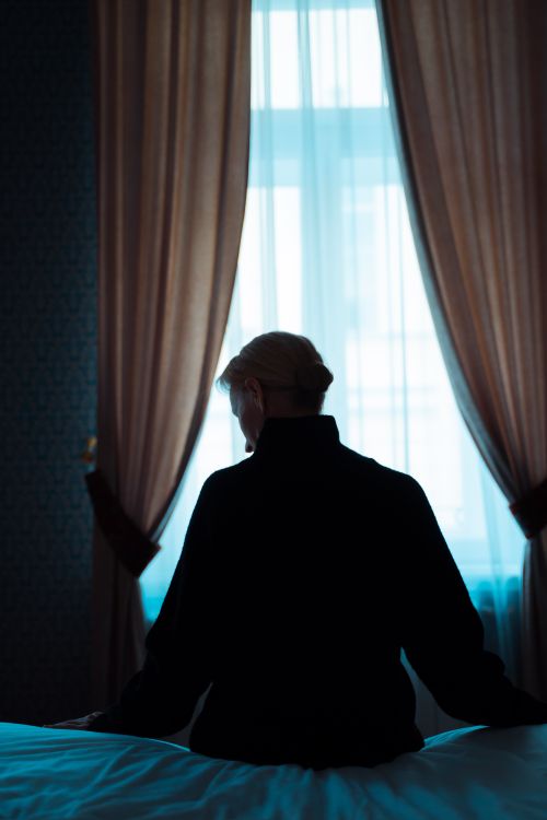 Free Silhouette of a woman sitting in a dimly lit room, conveying a sense of introspection and solitude. Stock Photo