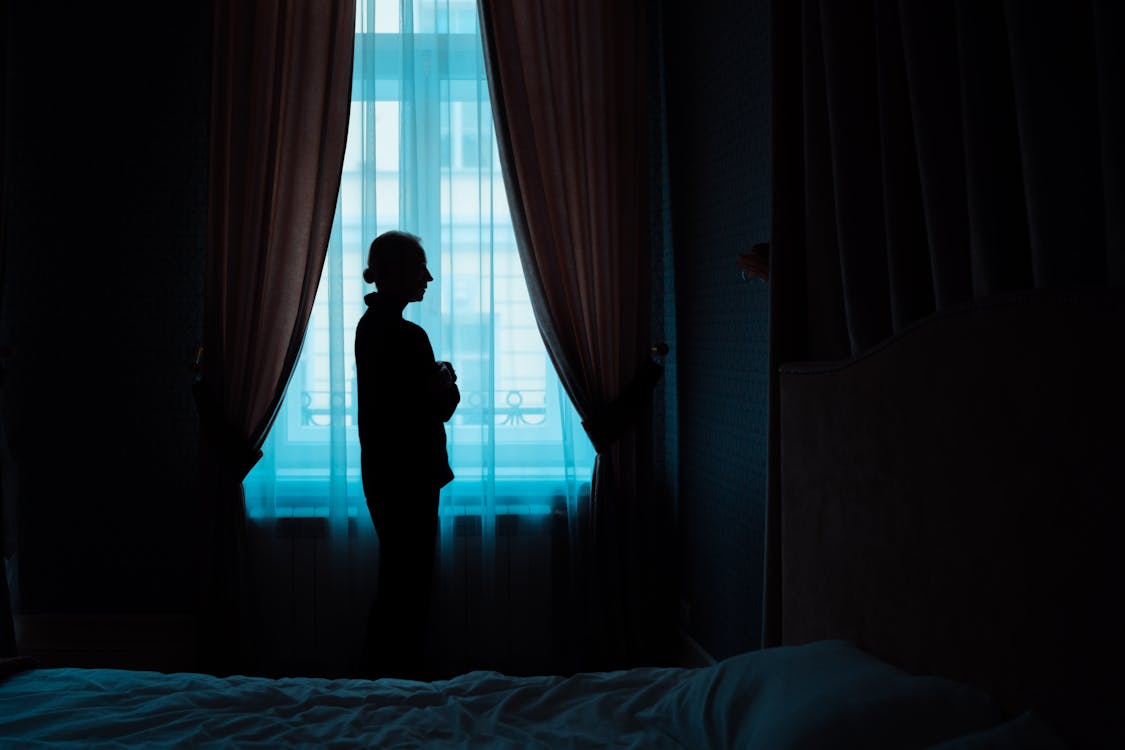 Free Silhouette of a Woman Standing Near the Window Stock Photo