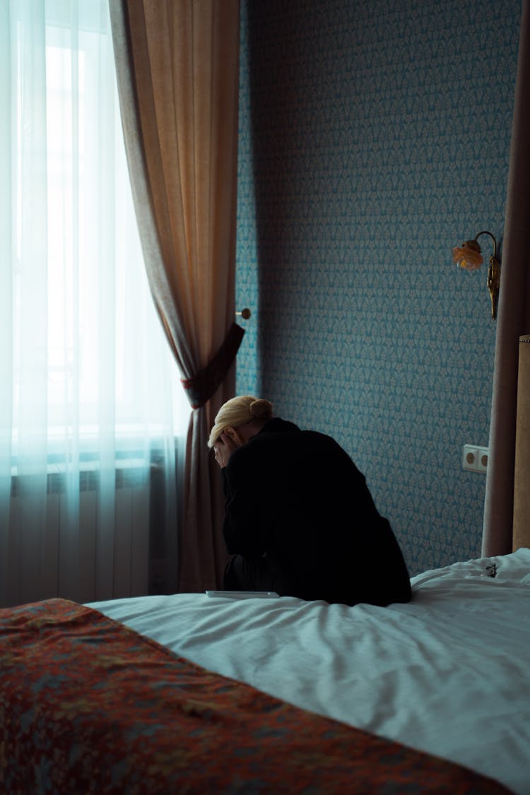 A Woman Sitting Alone On Her Bed Looking Depressed