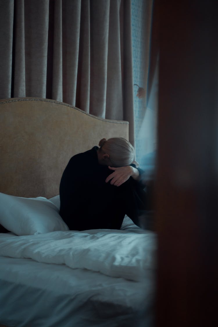 A Woman Sitting Alone On Her Bed Looking Depressed