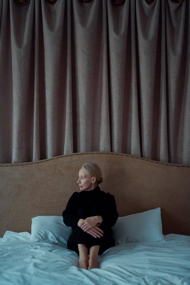 A Woman Sitting Alone On Her Bed Looking Depressed