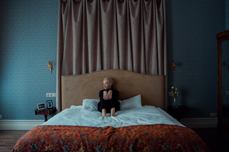 A Woman Sitting Alone On Her Bed Looking Depressed