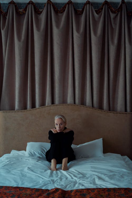 Woman in Black Clothing Sitting on the Bed