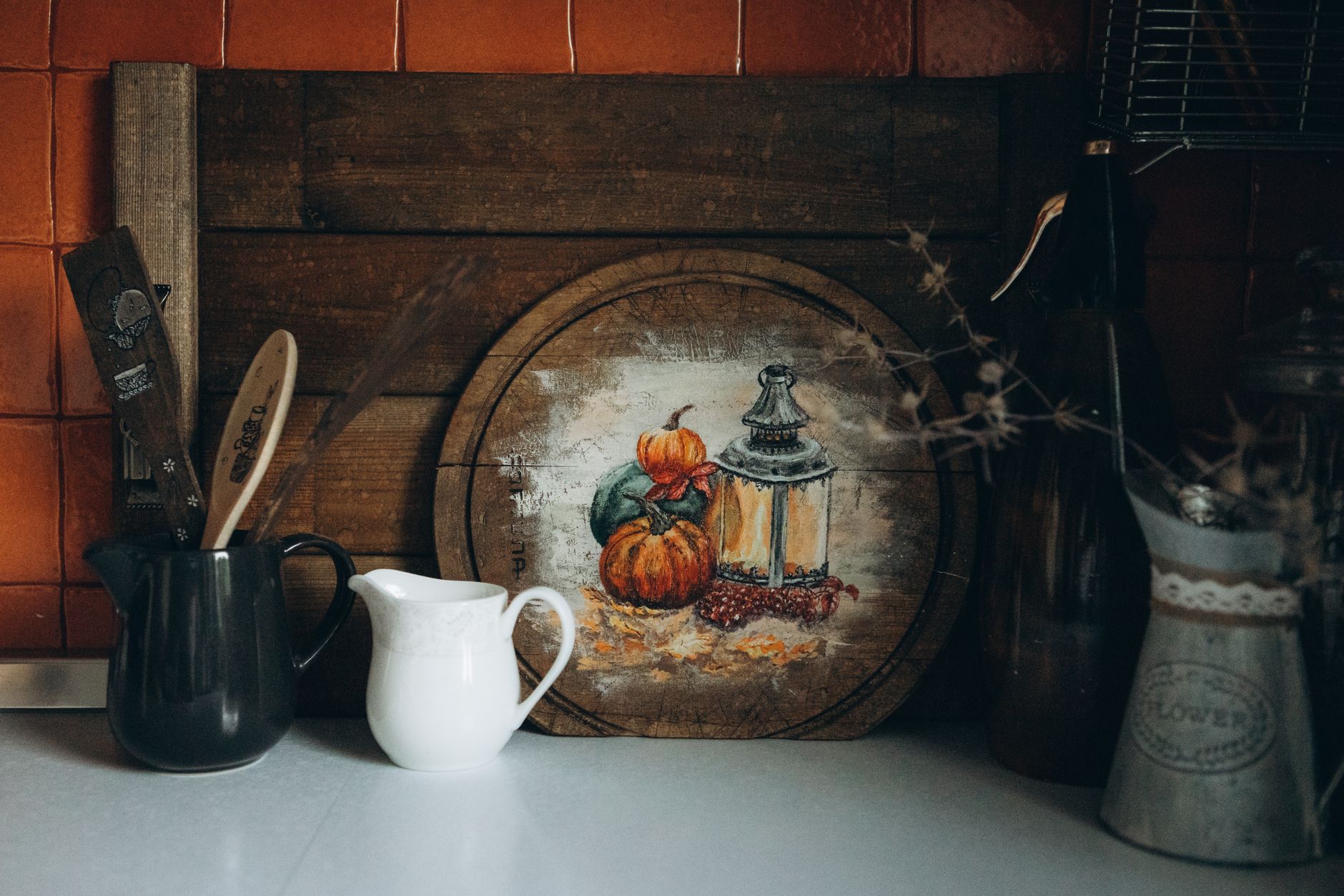 A cozy autumn-themed kitchen setup featuring rustic decor with pumpkins and a lantern.