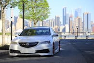 一辆银色定制讴歌停靠在城市天际线前，展现了都市的汽车文化