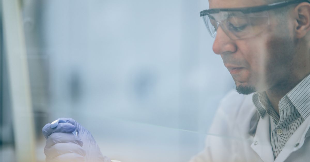 Research scientist wearing safety glasses and gloves in a laboratory setting.