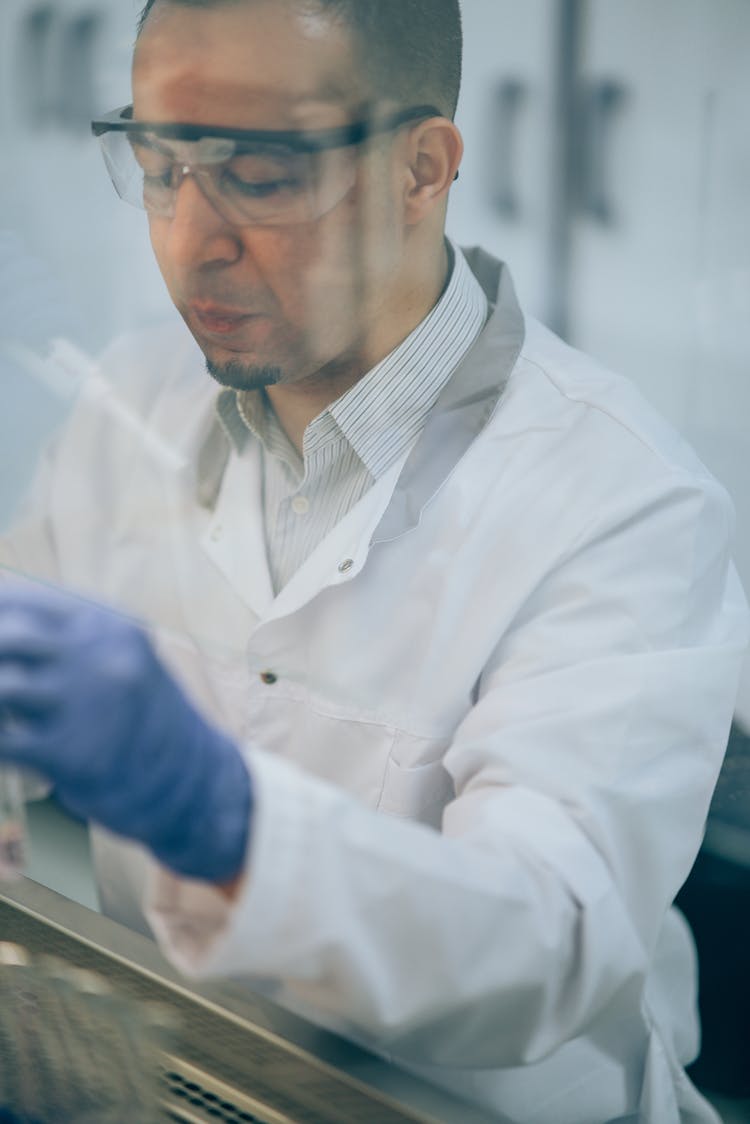 A Man Wearing Protective Goggles And Lab Coat