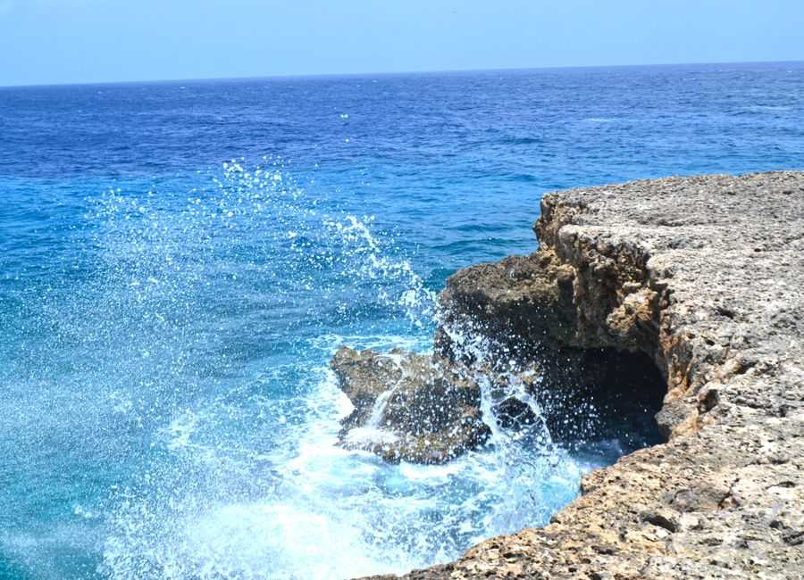 Vibrant ocean waves splashing against the rocky shoreline of Curaçao. A perfect tropical seascape for travel inspiration.