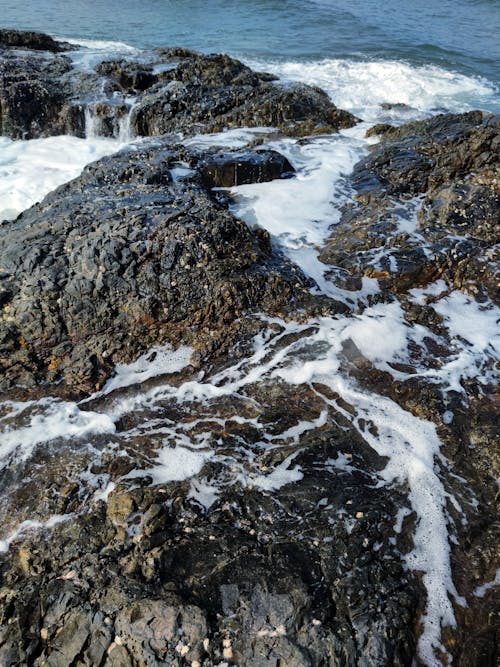 Foto profissional grátis de espuma do mar, pedras, tiro vertical