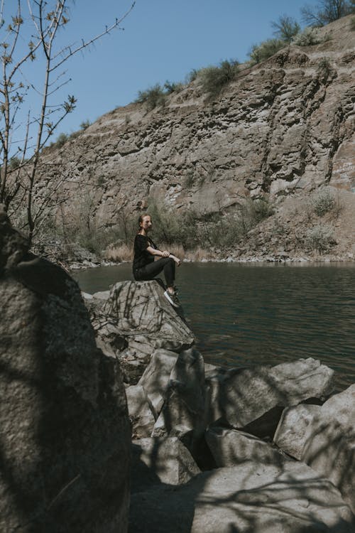 Woman Sitting on a Rock Near the River