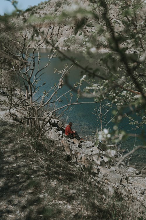 Free Man Sitting on Rocks by a River Stock Photo
