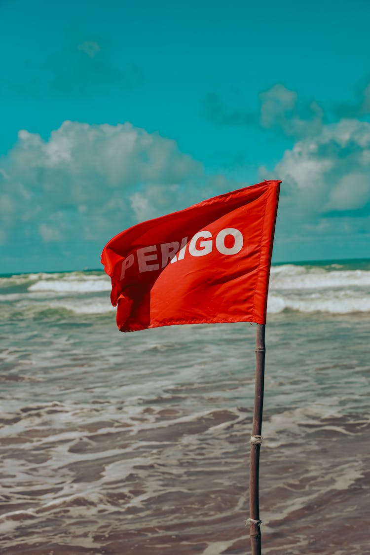 Red Flag Warning Sign On The Beach