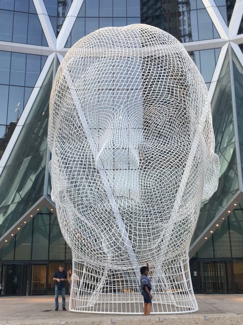 Free A large modern head sculpture in front of a glass building in Calgary. Stock Photo