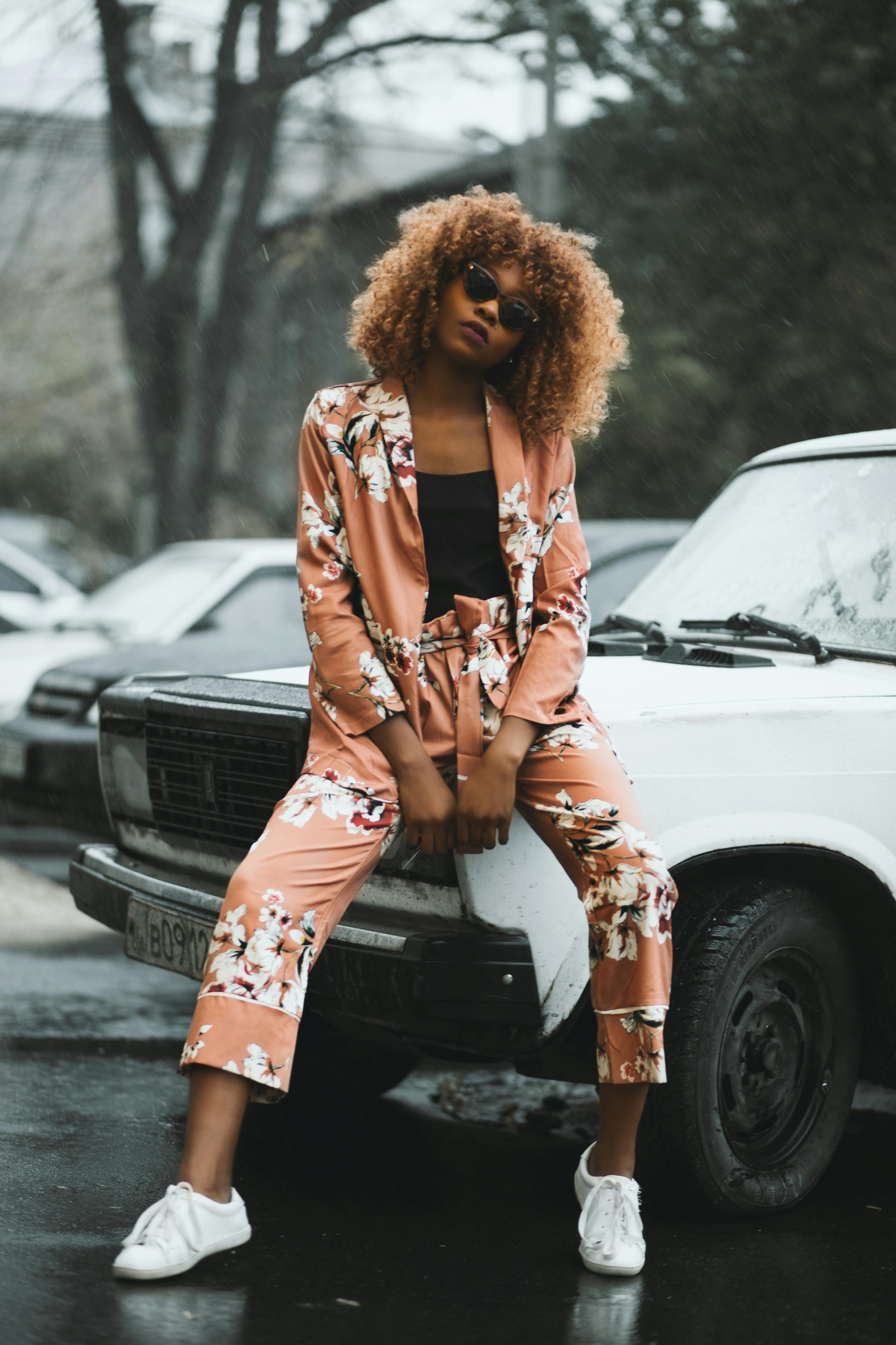 一位身着花卉套装的时尚女性在城市的老爷车旁摆出时尚姿势