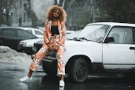 一位穿着花卉套装的时尚女士在雨天对着老爷车摆姿势