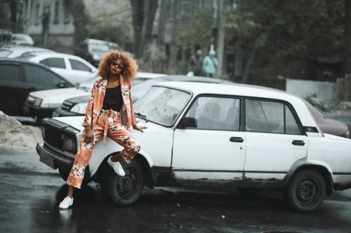 Free Fashion-forward woman leans against a vintage car in Kharkiv, showcasing urban style. Stock Photo