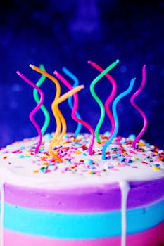 Colorful spiral candles top a decorated cake with sprinkles, perfect for festive occasions.