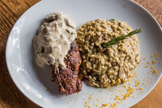 Delicious steak topped with sauce served with creamy mushroom risotto. Italian cuisine on a white plate.