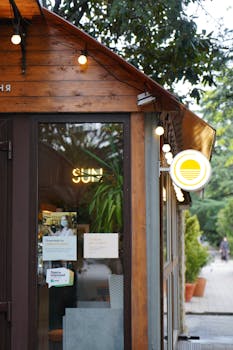 A picturesque wooden exterior of a cozy coffee shop with plants and charming lights.