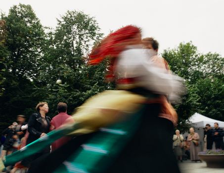 Vibrant outdoor celebration featuring traditional dance with colorful costumes and motion blur.