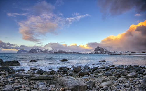 Rocky Shore Near Mountain during Sunset