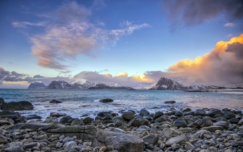 Free Explore the stunning rocky seashore of Nordland, Norway with snow-capped mountains under a vivid sky. Stock Photo