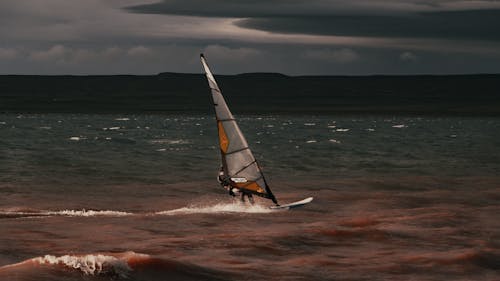 Person Riding on White and Brown Sailing Board