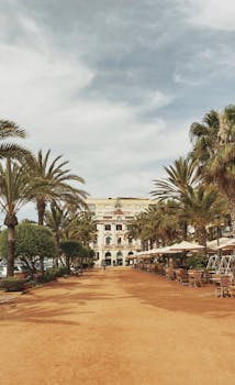 Picturesque view of a palm-lined walkway leading to a historic building in Lloret de Mar, Spain.