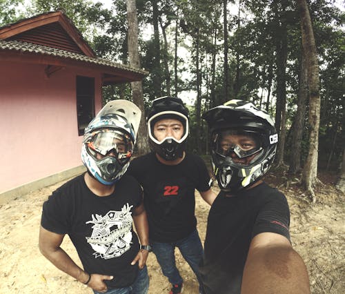 Three Men Wearing Helmet Standing Near House Outdoor