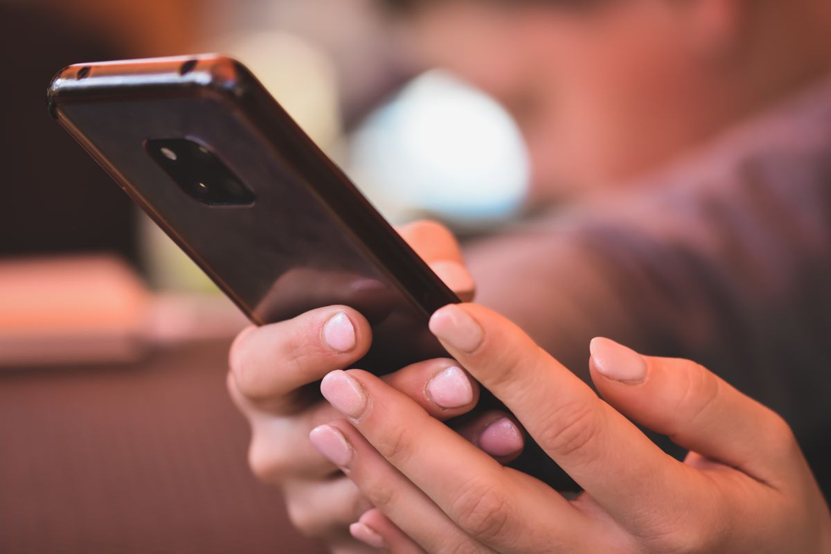 Akıllı telefon tutan genç bir kişinin eller ve ekran odaklı fotoğrafı
