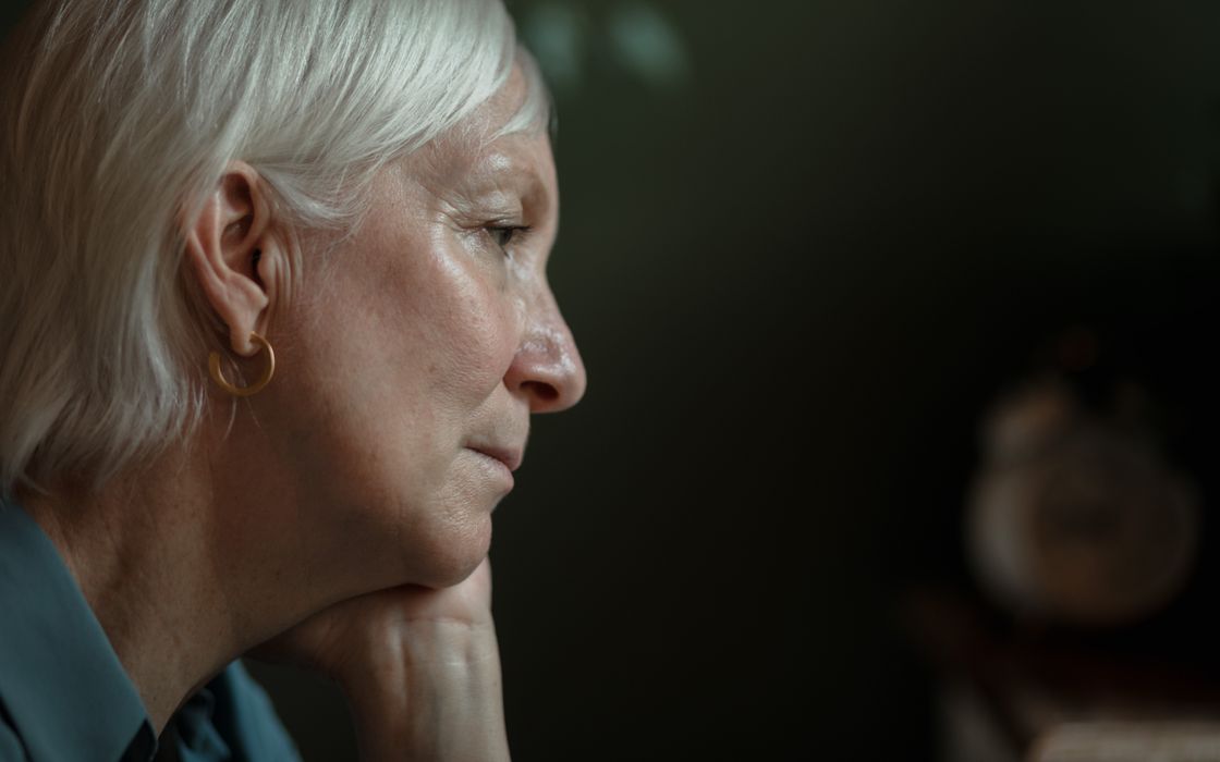 Senior woman with white hair seen in side profile, showing the jawline and neck