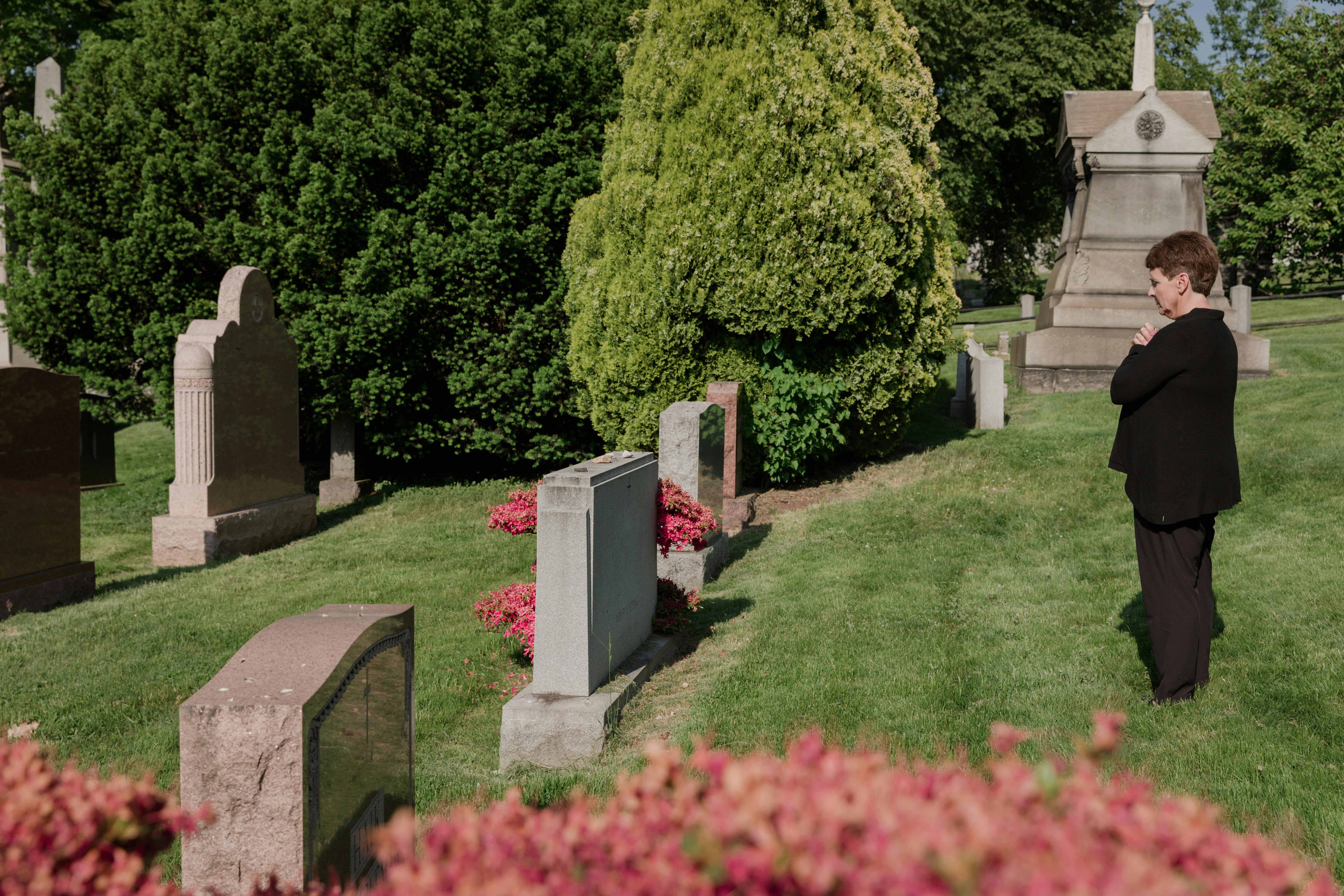 Woman In Black Outfit Standing In Front Of A Grave