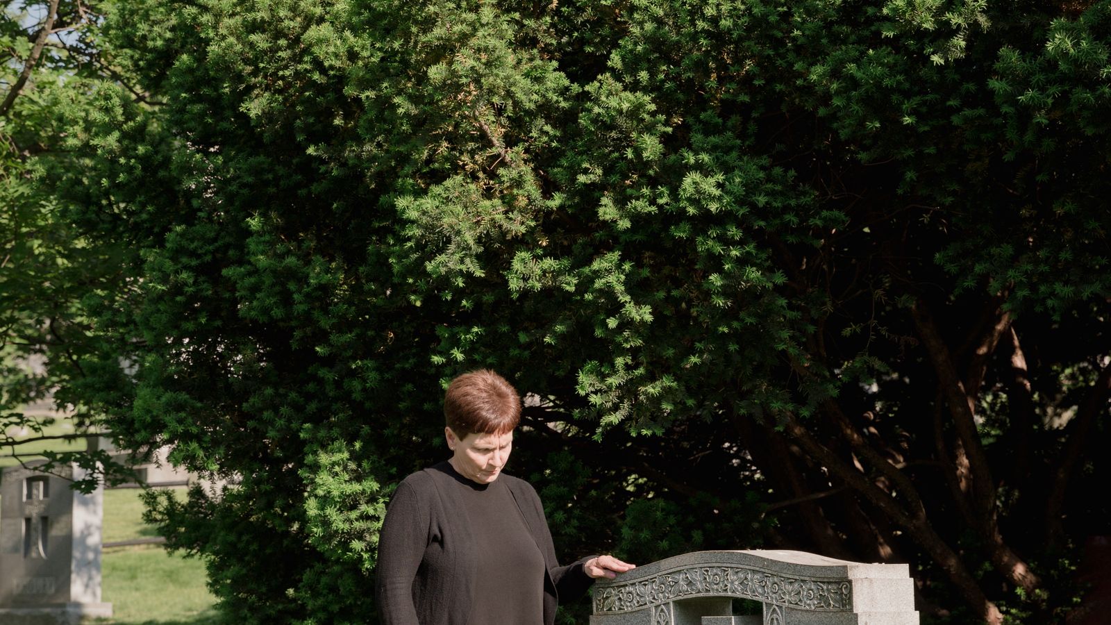 Woman in black long sleeves and pants standing near tomb, Madagascar