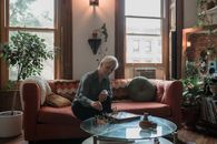 Woman in Gray Long Sleeve Shirt Sitting on Red Couch