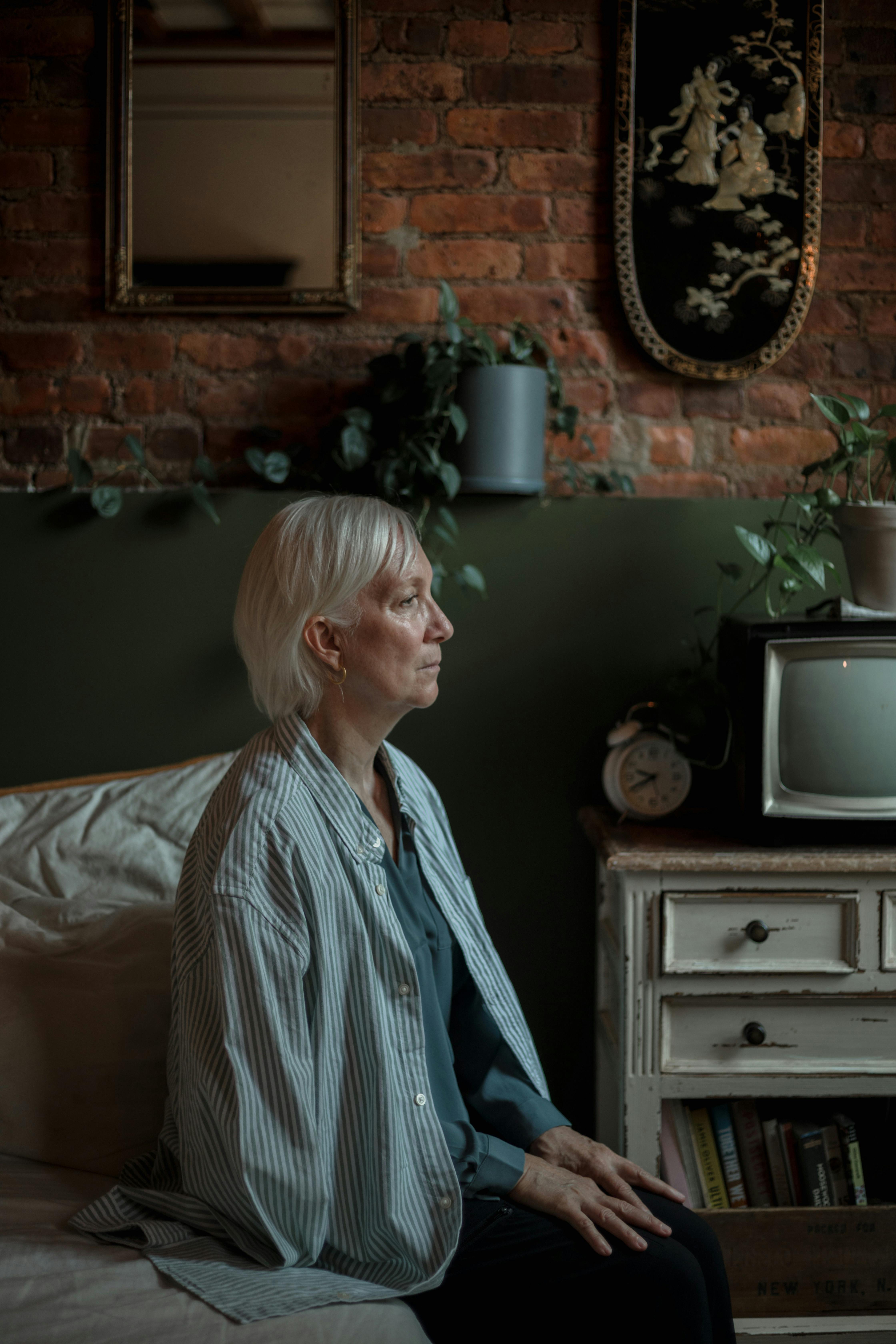 elderly woman sitting on side of bed feeling lonely