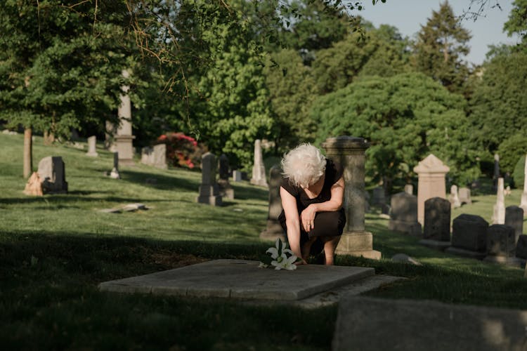 Woman In Black Dress Offering Flowers On A Grave