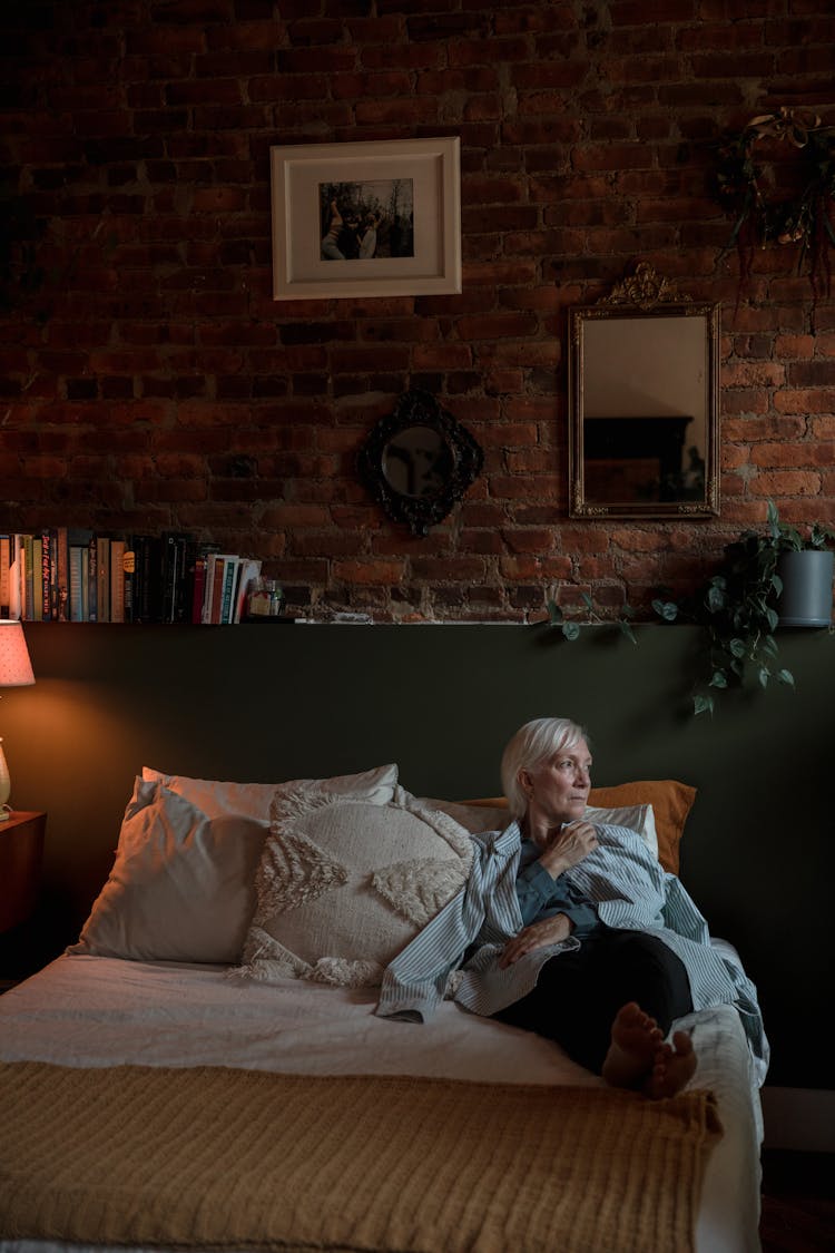 An Elderly Woman Lying On A Bed