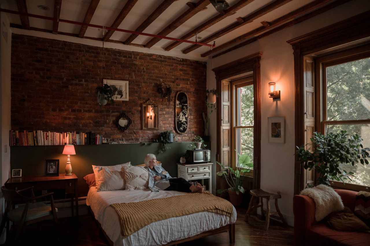 Moody brick loft bedroom with wood beams and vintage mirrors